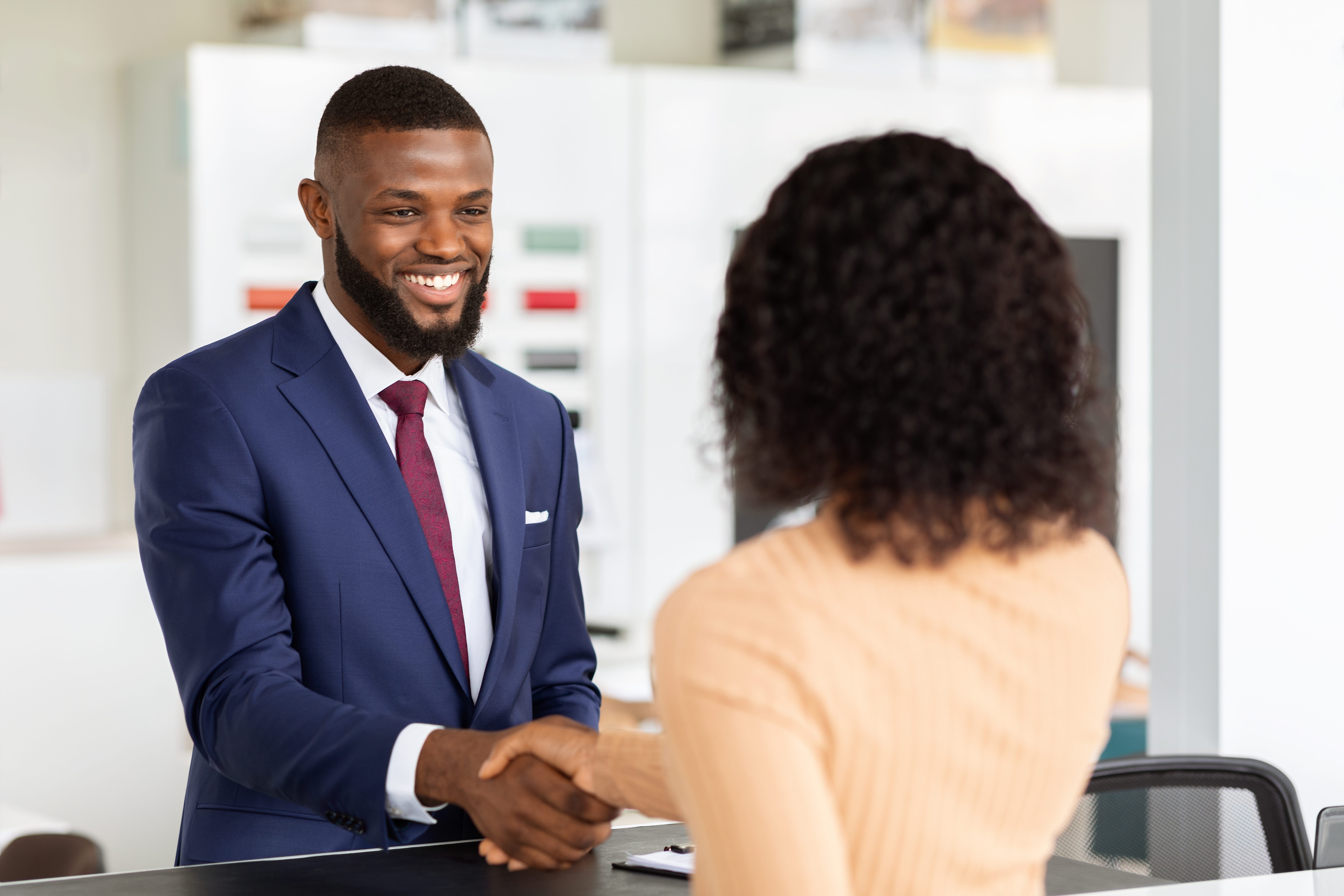 Smiling Car Seller Shaking Hands With Female Customer After Successful Deal